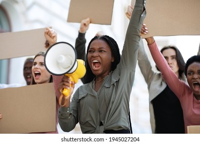 Furious multiracial students with empty placards having strike or demonstration on the street. Motivated african american woman with loudspeaker chanting slogans over demonstrating crowd outdoors