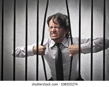 Furious strong businessman bending the bars of his prison