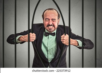 Furious Strong Middle Aged Businessman Bending Bars Of His Prison Cell Grey Wall Background. Life Limitations, Law Violation Infringement Tax Evasion Consequences Concept. Face Expression Emotion  