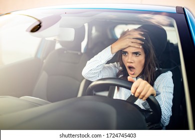 Furious woman stucked in traffic jam. A furiously angry woman driving grimaces, shaking her fist through the windscreen in a bout of road rage! Road rage traffic jam concep