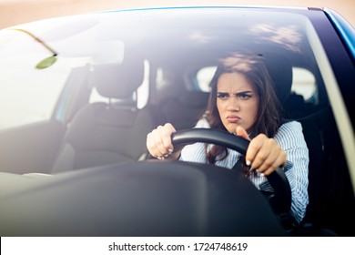 Furious Woman Stucked In Traffic Jam. A Furiously Angry Woman Driving Grimaces, Shaking Her Fist Through The Windscreen In A Bout Of Road Rage! Road Rage Traffic Jam Concep