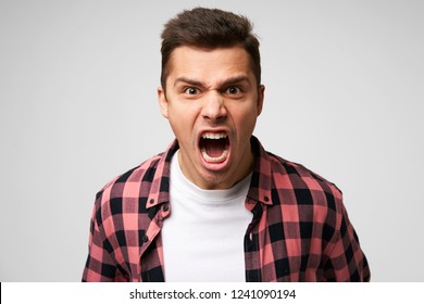 Furious,enraged man with grumpy grimace on his face,with mouth opened in shout, ready to argue and swear, wants to gain respect, show strength, isolated over white background