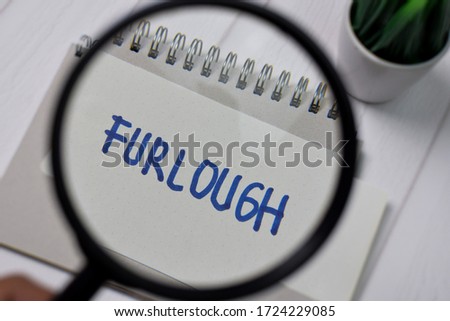 Furlough write on sticky notes with magnifying glass isolated on office desk