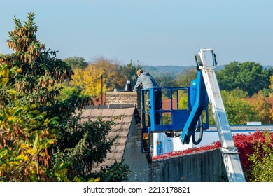 Furnace Repairman Repairing A Chimney At A Height While Standing On A High-altitude Lift.