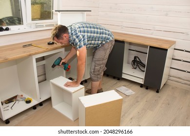 A Furniture Assembler Assembles Modern Kitchen Furniture In A Private Home