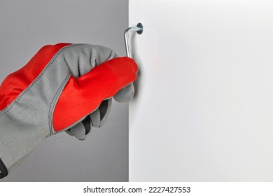 Furniture assembler in red gloves is screwing in a screw with a hex wrench. Assembly of new furniture with copy space.