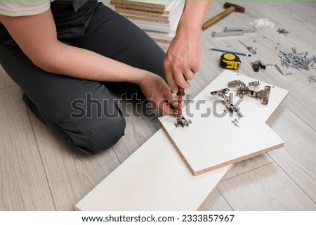 Furniture assembly. A worker is screwing a hinge with a screwdriver into a wooden closet door. Adjustment of fittings [[stock_photo]] © 