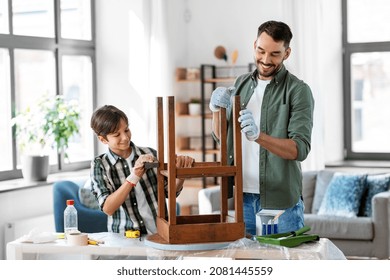 furniture renovation, diy and home improvement concept - happy smiling father and son sanding old round wooden table with sponge at home