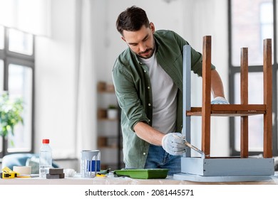 furniture renovation, diy and home improvement concept - man in gloves with paint brush painting old wooden table in grey color - Shutterstock ID 2081445571