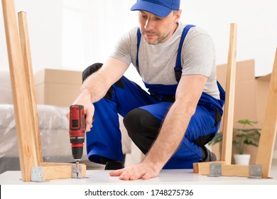 Furniture Repair And Assembly. Workman Fixing Table Using Electric Drill Assembling And Furnishing Home After Renovation Indoor - Powered by Shutterstock