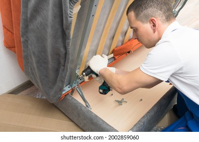 a furniture repair worker replacing the creaking mechanism of an upholstered sofa