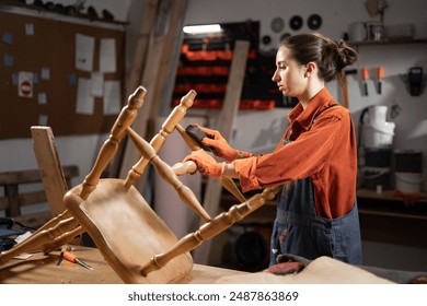 furniture restoration concept. Caucasian woman restoring old wooden chair in her carpenter workshop. Copy space - Powered by Shutterstock