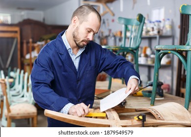 Furniture Restorer Using Drawing On Paper In Process Of Renovation Old Chair In Workshop