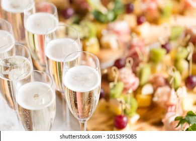 Furshet. Table top full of glasses of sparkling white wine with canapes and antipasti in the background. champagne bubbles