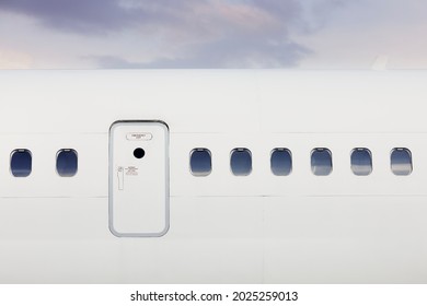 Fuselage of airplane with door and windows. Plane against moody sky.