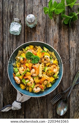 Fusilli with prawns, mango, avocado and mint on wooden table 