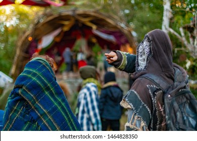 Fusion Of Cultural & Modern Music Event. Spiritual Hippies Are Viewed From Behind, One Gives The V Peace Hand Gesture As They Watch Musicians Perform At A Festival That Fuses Native And Modern Culture