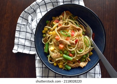 Fusion Food Style Of Thai Green Curry Spaghetti With Mixed Vegetables Included Carrot, Green Beans, Peas, Corn And Green Chillies With A Fork In A Bowl. Flat Lay Top View And Food From Above Concept.