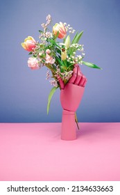 Fusion of modern life and nature. Pink mannequin hand holding colorful flower bouquet. Minimal creative background.