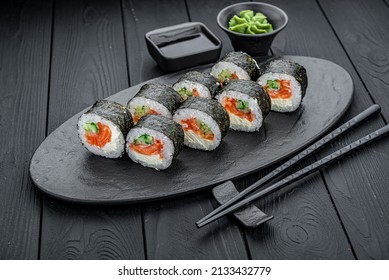 Futomak with salmon, rice and nori seaweed on the dark background.