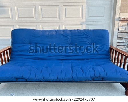 futon and frame on the sidewalk driveway of a house for free pickup 