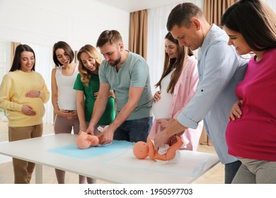 Future fathers and pregnant women learning how to swaddle baby at courses for expectant parents indoors
