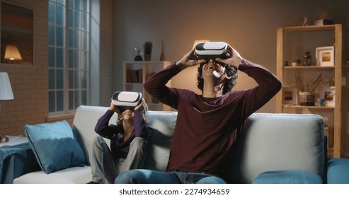 Future is now. Funny south asian siblings or father and son with curly hair are trying virtual reality headsets, having fun playing video games - modern technologies, family time concept 