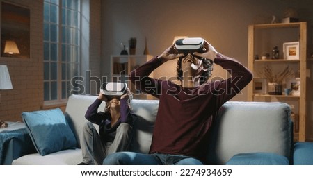 Future is now. Funny south asian siblings or father and son with curly hair are trying virtual reality headsets, having fun playing video games - modern technologies, family time concept 