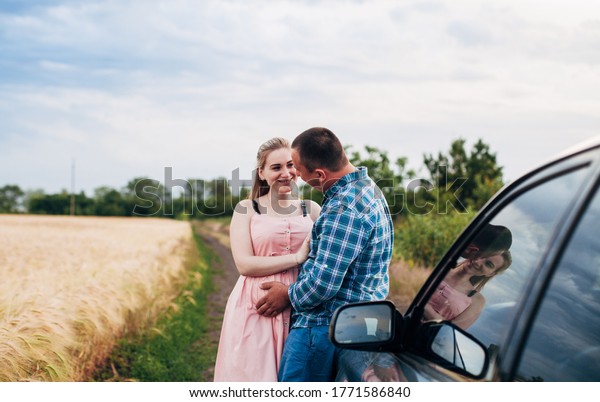 \
future parents near\
the car in the field