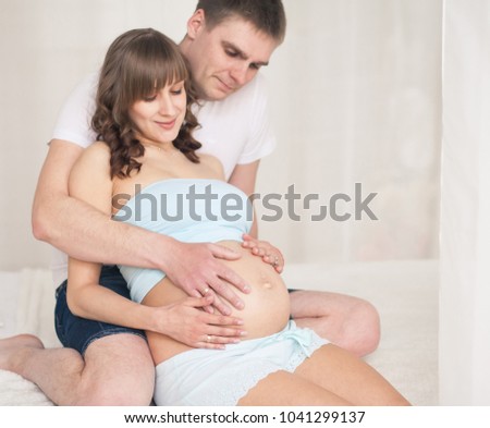 Pregnant woman embraced by her husband