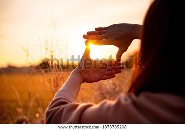 Future planning\
concept, Close up of woman hands making frame gesture with sunset,\
Female capturing the\
sunrise.