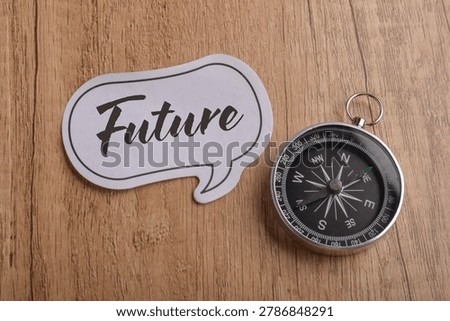 Future planning concept with compass and speech bubble label on wooden background representing direction, ambition, strategy, forecasting, and long term vision.