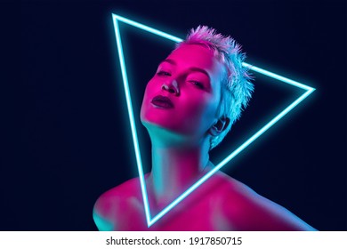 Future  Portrait female fashion model in neon light and neoned blue glowing triangle dark studio background  Beautiful woman and trendy make  up   well  kept skin  Vivid style  beauty concept 