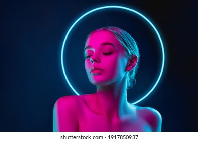 Future  Portrait female fashion model in neon light and neoned blue glowing circle dark studio background  Beautiful woman and trendy make  up   well  kept skin  Vivid style  beauty concept 