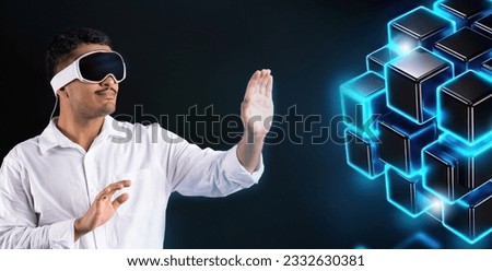 Future technology and business concept. Young businessman wearing vision pro virtual reality glasses touching blue glowing holographic cubes, planning business strategy in futuristic way, panorama