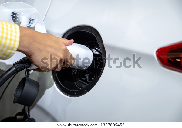 Future Vehicles concept : hand\
holding a plug for plug-in charging a batteries of electric\
car.