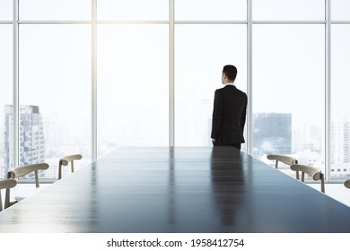 Future vision concept with businessman looking on city skyscrapers through big window in spacious conference room