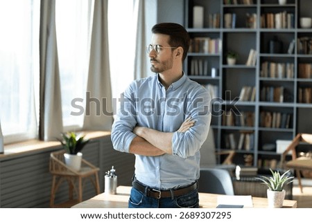 Future vision and forward thinking. Pensive young man business professional entrepreneur ceo stand in office workplace with arms crossed visualize big project success plan long term strategy set goals