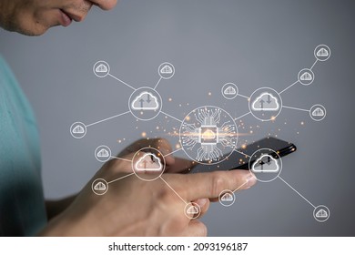Futuristic cloud computing storage system concept, business man hand holding smartphone with interface cloud icon, connect to data base station and operations use artificial intelligence or AI system.