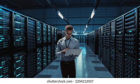 Futuristic Concept: Big Data Center Chief Technology Officer Holding Laptop, Standing In Warehouse, Information Digitalization Lines Streaming Through Servers. SAAS, Cloud Computing, Web Service - Powered by Shutterstock