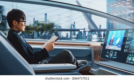 Futuristic Concept: Handsome Stylish Japanese Businessman in Glasses Reading Notebook and Watching News on Augmented Reality Screen while Sitting in a Autonomous Self-Driving Zero-Emissions Car. - Powered by Shutterstock