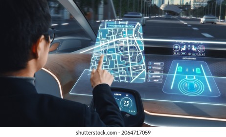 Futuristic Concept: Stylish Businessman Setting Location on an Interactive Navigation App on an Augmented Reality Dashboard while Sitting in an Autonomous Self-Driving Zero-Emissions Electric Car. - Powered by Shutterstock