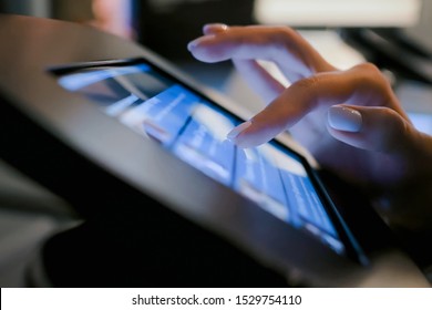 Futuristic, education, entertainment, learning, technology concept. Woman hand using touchscreen display of interactive floor standing black tablet kiosk at exhibition or museum - side close up view
