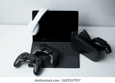 A futuristic gaming setup showcasing a tablet with keyboard, white over-ear headphones, two black game controllers, and a virtual reality headset. Perfect for illustrating cutting-edge gaming technolo - Powered by Shutterstock - Get 15% off with code: PIKWIZARD15