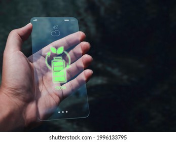 Futuristic modern transparent glass phone Technology concept. Renewable energy with wireless battery charging icon on a future slim smartphone with copy space, eco-friendly device concept. - Powered by Shutterstock