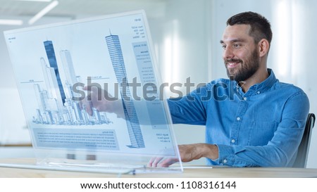In the Futuristic Office Male Architects Works on the Transparent Computer Display with Skyscraper Building Model. Technologically Advanced Office Professional People Use Modeling Software Application
