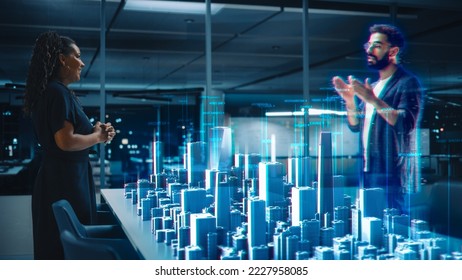 Futuristic Office Online Meeting Video Conference Call: Male and Female Real Estate Developers Talk using Augmented Reality. Global Business For Virtual Remote Work. Hologram of City Project Concept. - Powered by Shutterstock