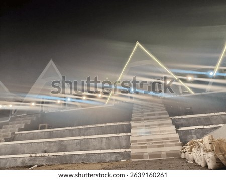 Futuristic outdoor space with neon triangular lights and string lights illuminating concrete steps at night, creating a unique, modern ambiance.
