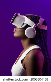 Futuristic side view portrait of young African-American woman wearing VR headset against purple background