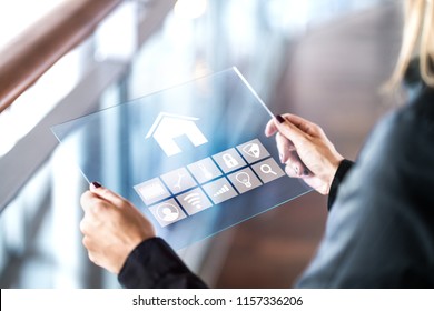 Futuristic smart home control inferface in transparent tablet. Person using digital automated system. Mobile glass device in modern house. Internet of things (IOT) application for household appliances - Powered by Shutterstock